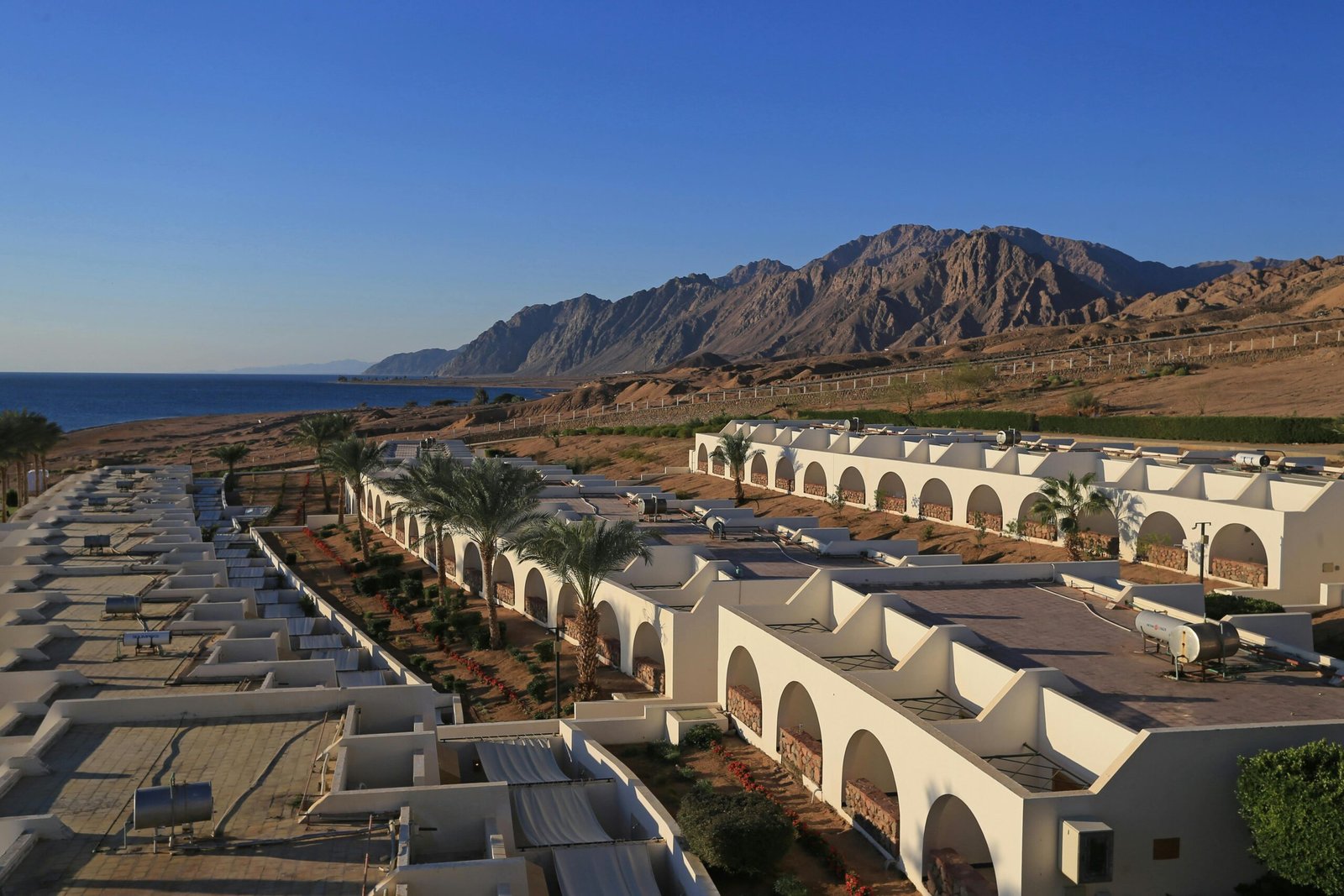 Image of Dahab beach with clear blue water and mountains in the background.