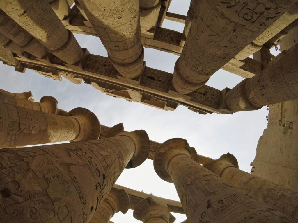 A panoramic view of the Karnak Temple Complex, with towering columns and ancient ruins under a golden sunset sky